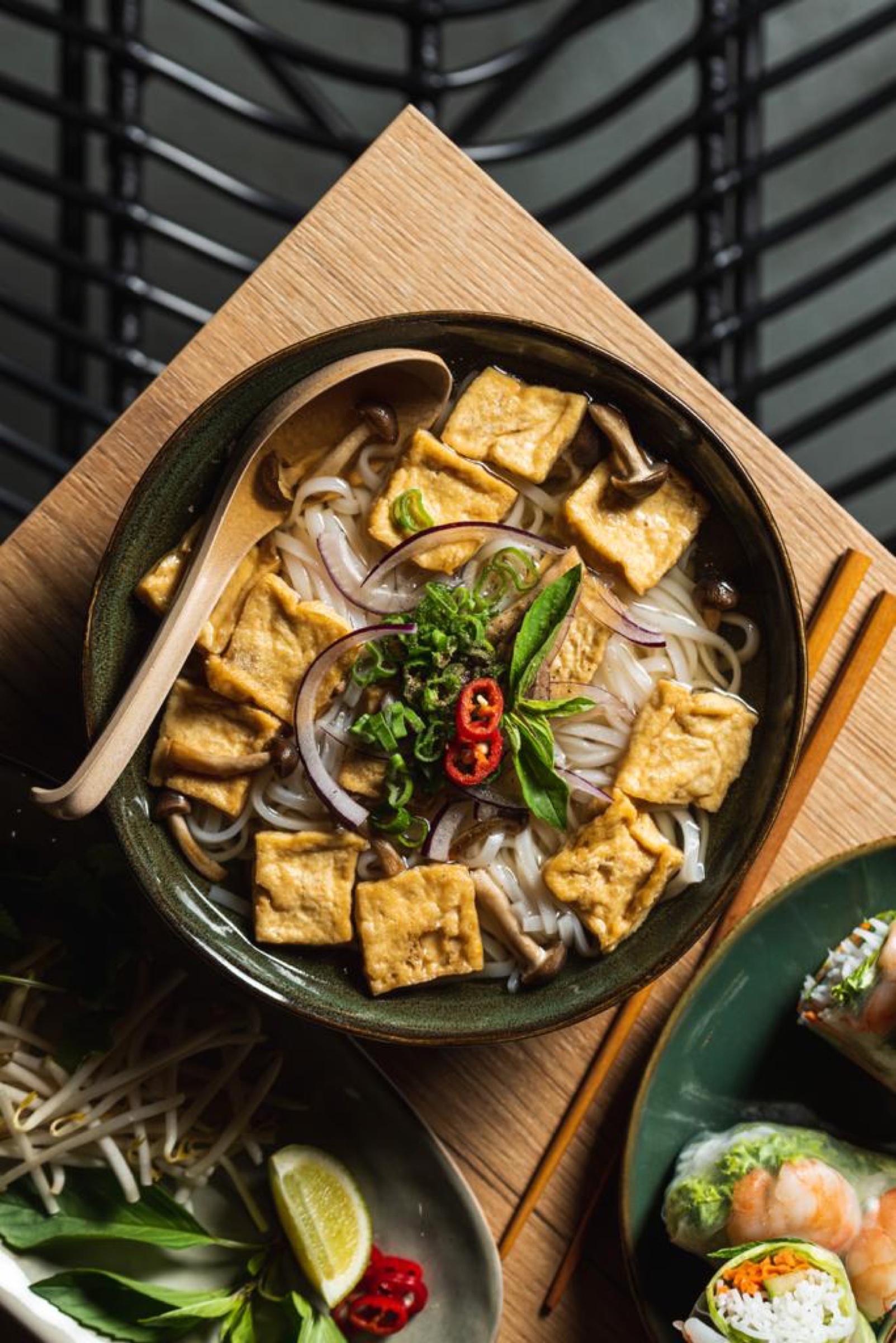 Vegan phở met tofu, geserveerd op een houten plank