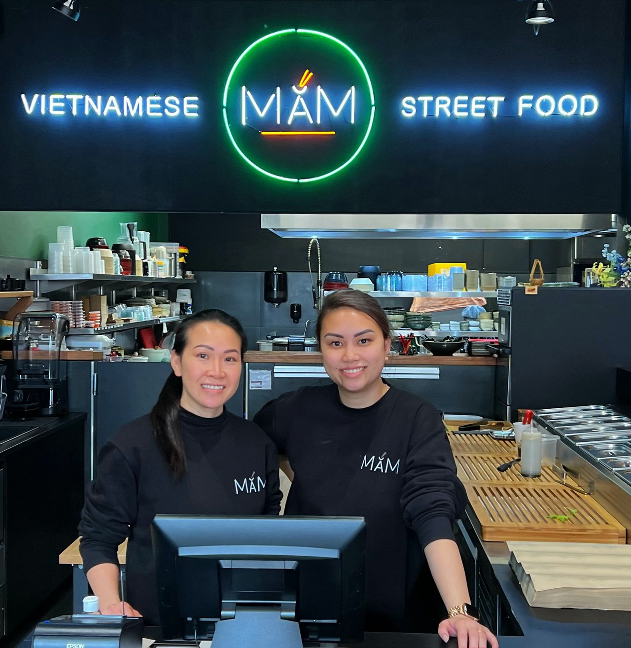 Hiền en Phi-Yến achter de toonbank van MẮM, onder de MẮM-neon in Nijmegen
